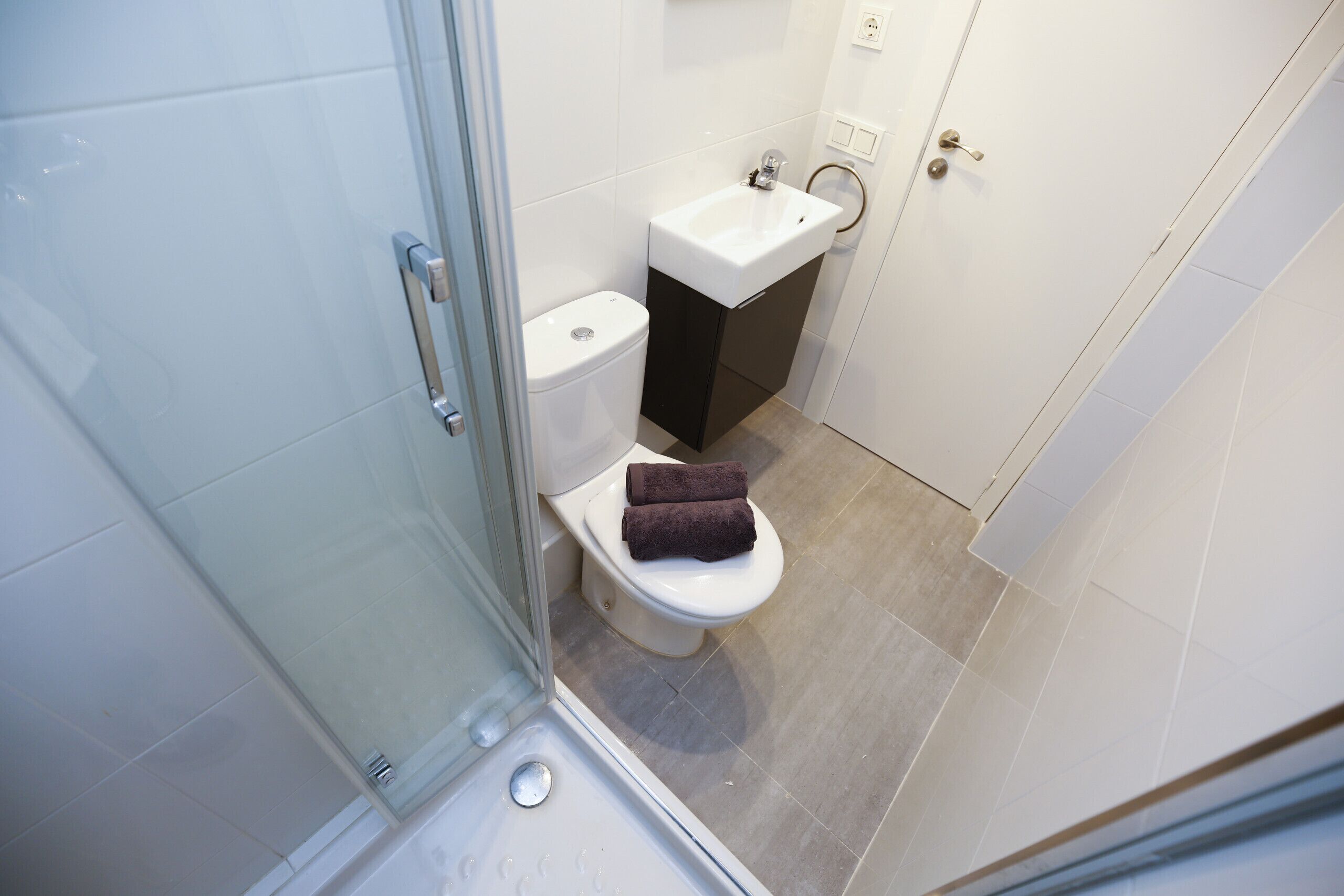 Un baño pequeño con inodoro, lavamanos y ducha.