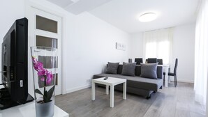 Een moderne woonkamer met een bank, salontafel en een televisie op een meubel.