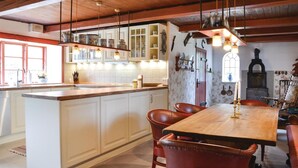 Eine Küche mit einer Holzinsel, weißen Schränken und einem Essbereich mit Holztisch und Ledersesseln.