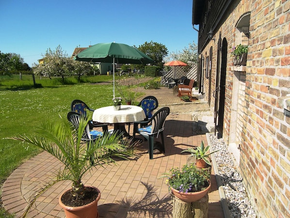 An outdoor patio with a round table, chairs, and potted plants.