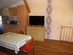 A compact kitchen with a dining area, a television, and a decorative wall panel.