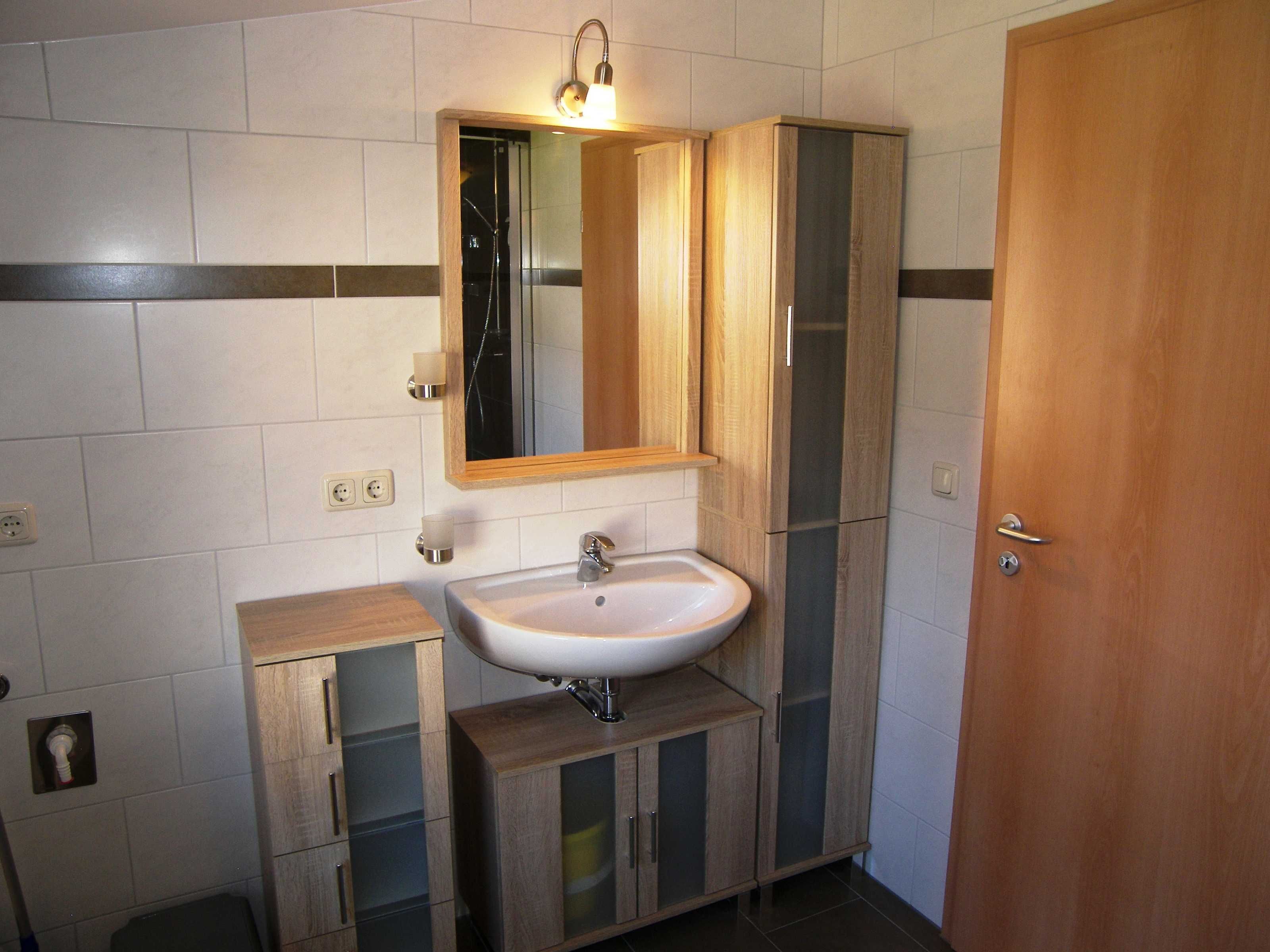 A bathroom with a sink, mirror, wooden cabinets, and a door.