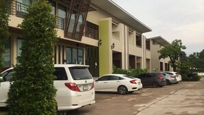 A building labeled "Family Residence" with a parking lot and several cars. - S Family Residence (Nikhom Kham Soi)