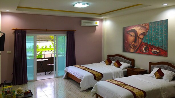 A hotel room with two beds, a balcony with a table and chairs, and a painting on the wall. - S Family Residence (Nikhom Kham Soi)