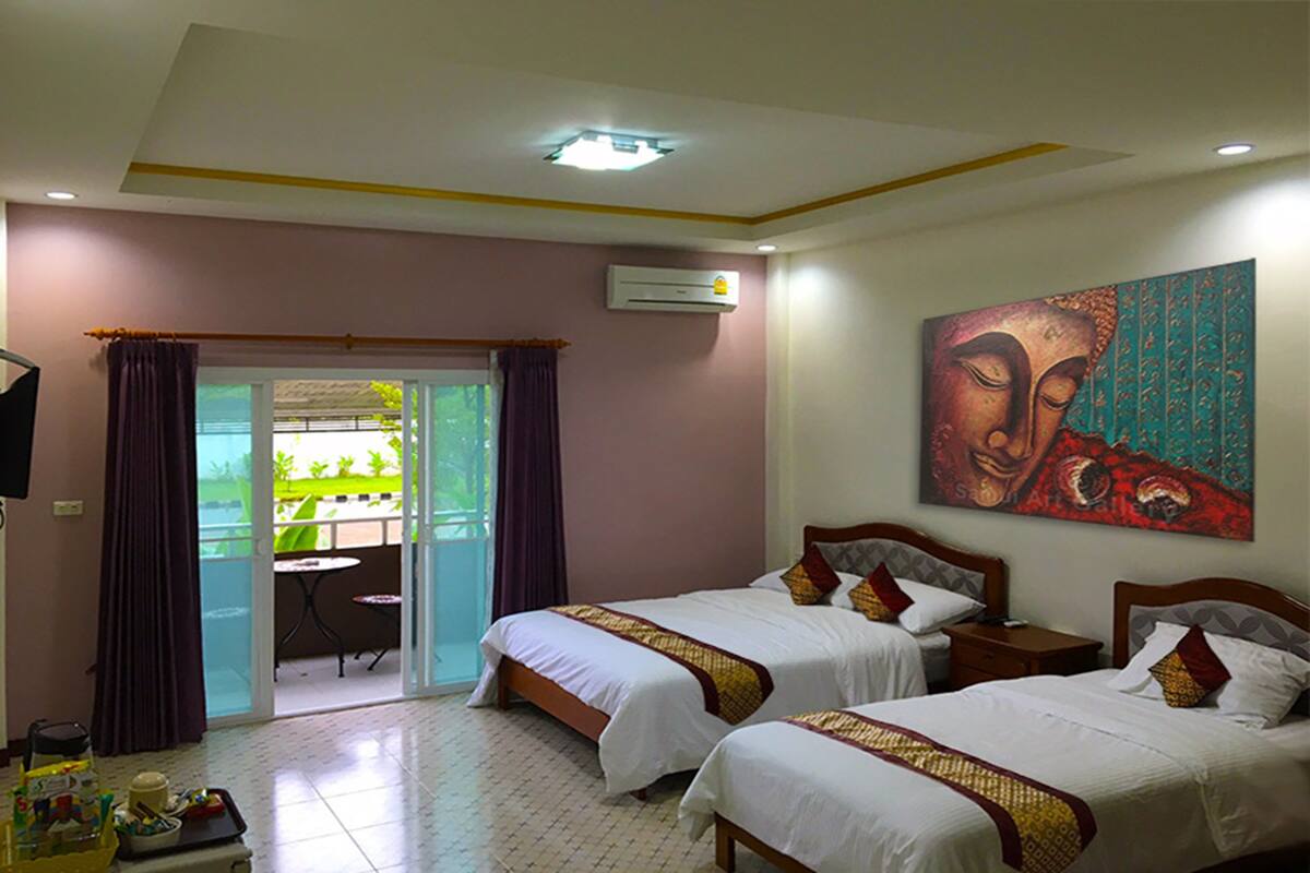 A hotel room with two beds, a balcony with a table and chairs, and a painting on the wall.