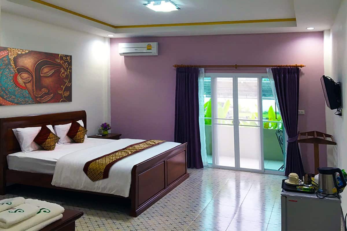 A hotel room with a large bed, a flat-screen TV, a ceiling fan, and a sliding glass door to the outside.