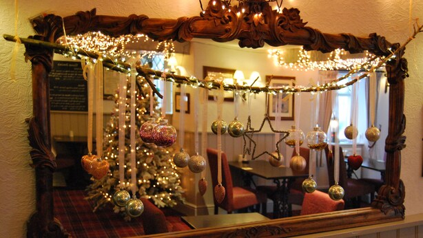 A mirror with a wooden frame, decorated with Christmas ornaments and lights. - The Miners Arms (Hope Valley)
