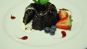 A dessert on a white plate with strawberries, blueberries, and a mint leaf garnish. - The Miners Arms (Hope Valley)