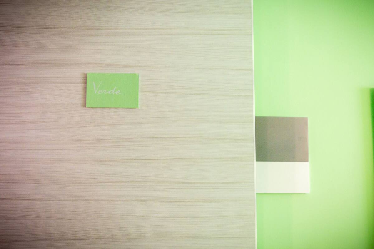 Una habitación con piso de madera y pared verde. Hay un letrero verde pequeño con la palabra 'Verde'.
