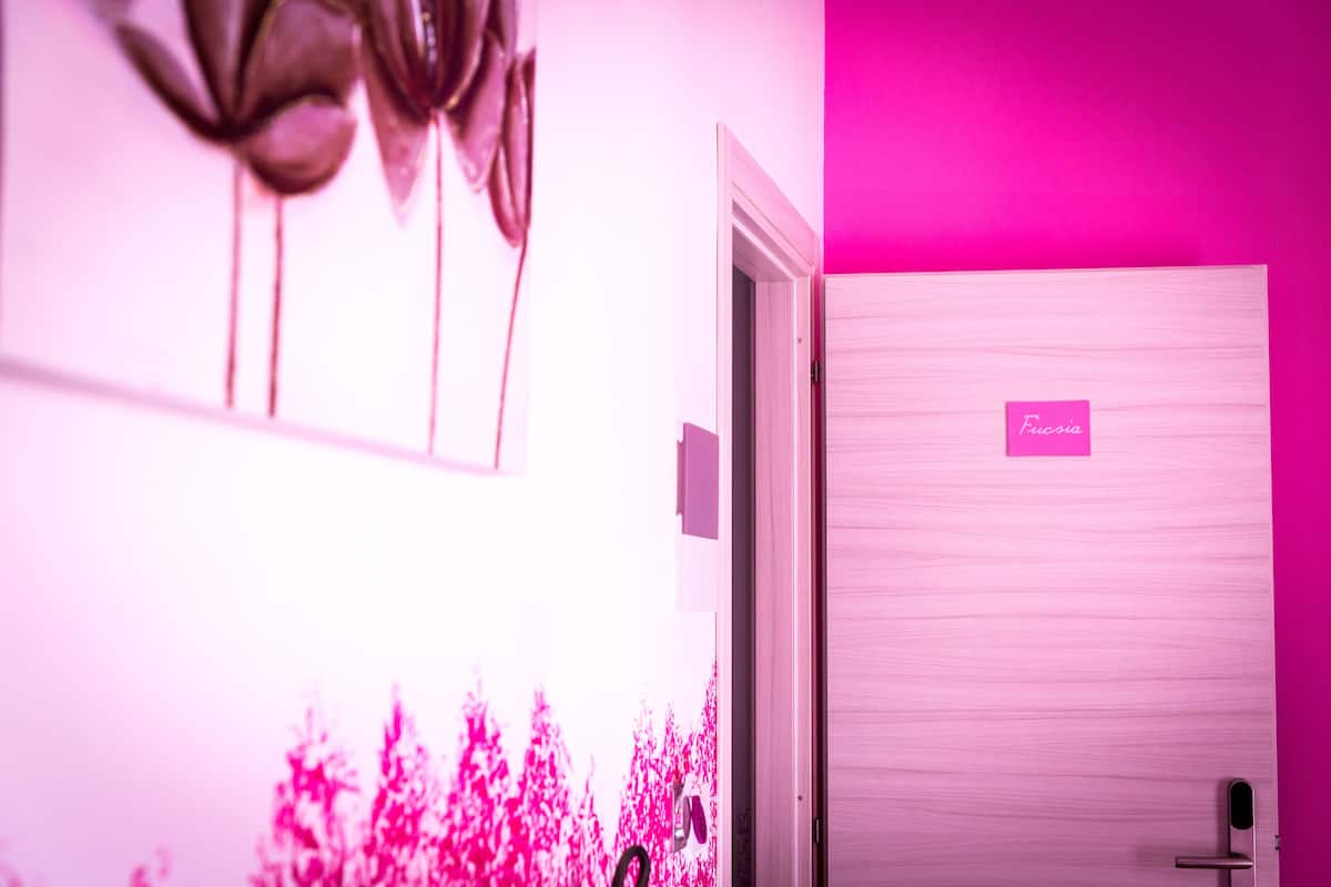Una habitación con pared rosa, una puerta con el rótulo "Fucsia" y un techo con diseño floral.