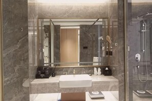 Un baño con encimera de mármol, un lavabo, un espejo, una ducha y una balanza.