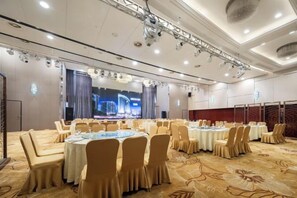 Une salle de banquet avec des tables rondes, des chaises et une scène.