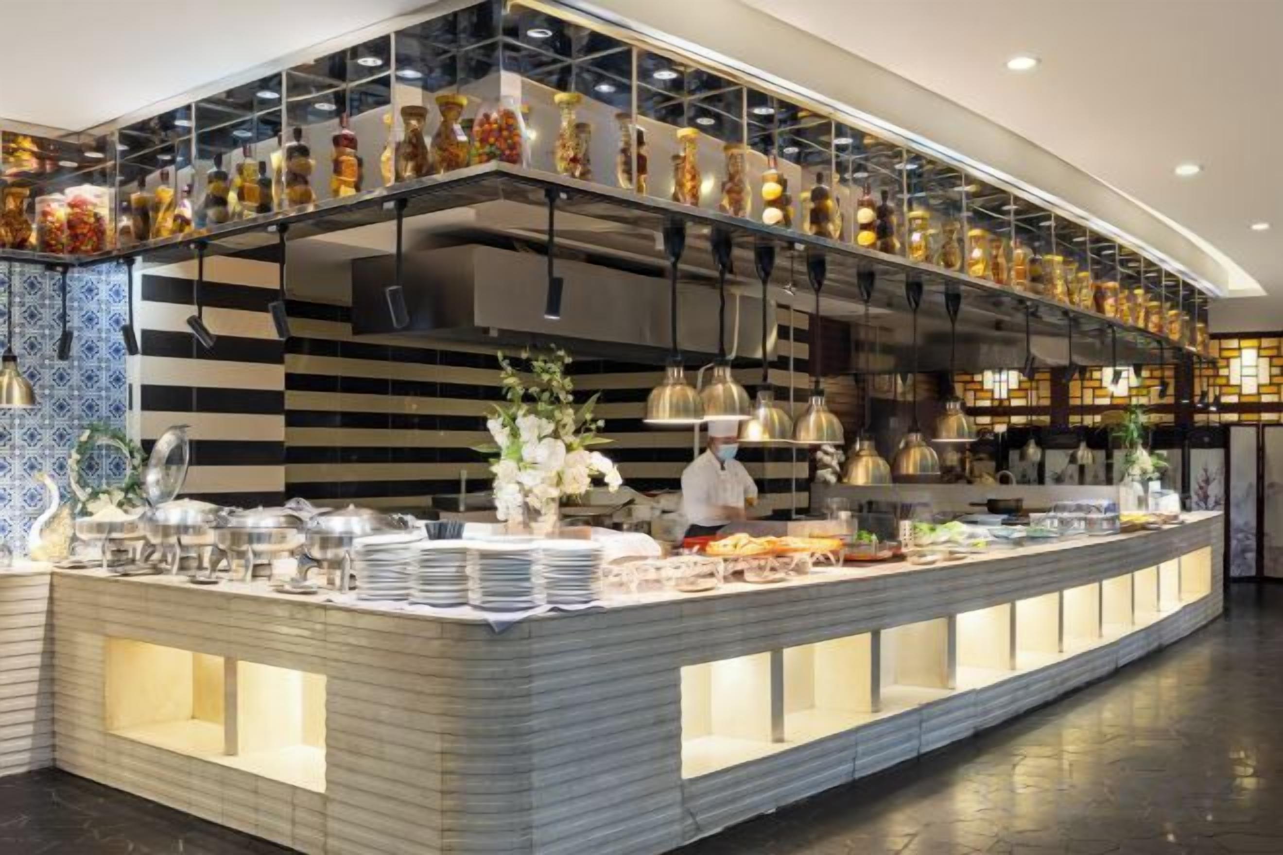 A buffet setup with a variety of food items and a chef preparing food.