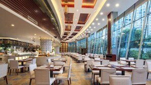 Un restaurante espacioso con una barra larga, varias mesas y un techo alto con iluminación empotrada.