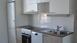A modern kitchen with white cabinetry, a stainless steel sink, a built-in oven, and a dishwasher.