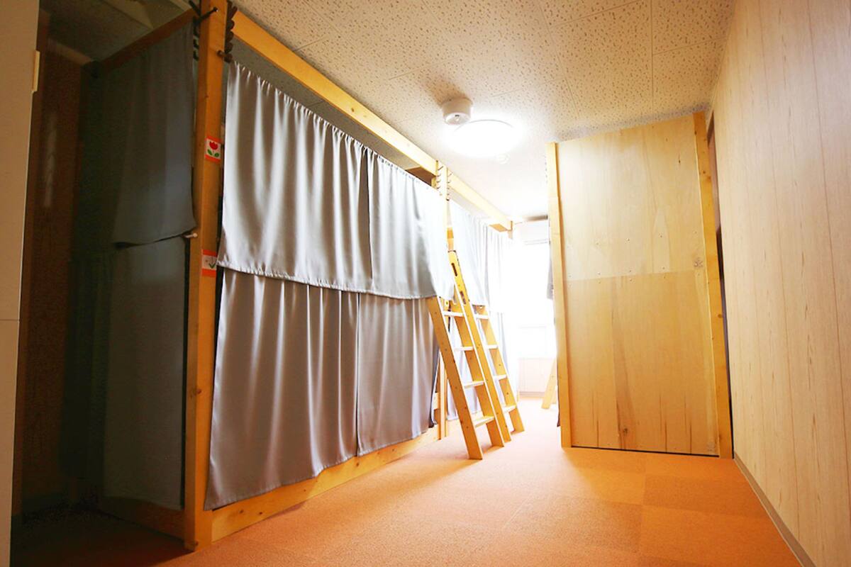 A hallway with a wooden floor, a door, and a curtain.