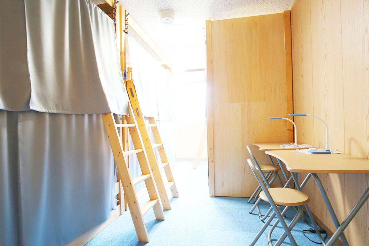 A room with a blue carpet, wooden walls, a desk with a chair, and a ladder.