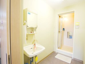 A small bathroom with a sink, mirror, and shower. - Hostel J Culture168 (Toyonaka)