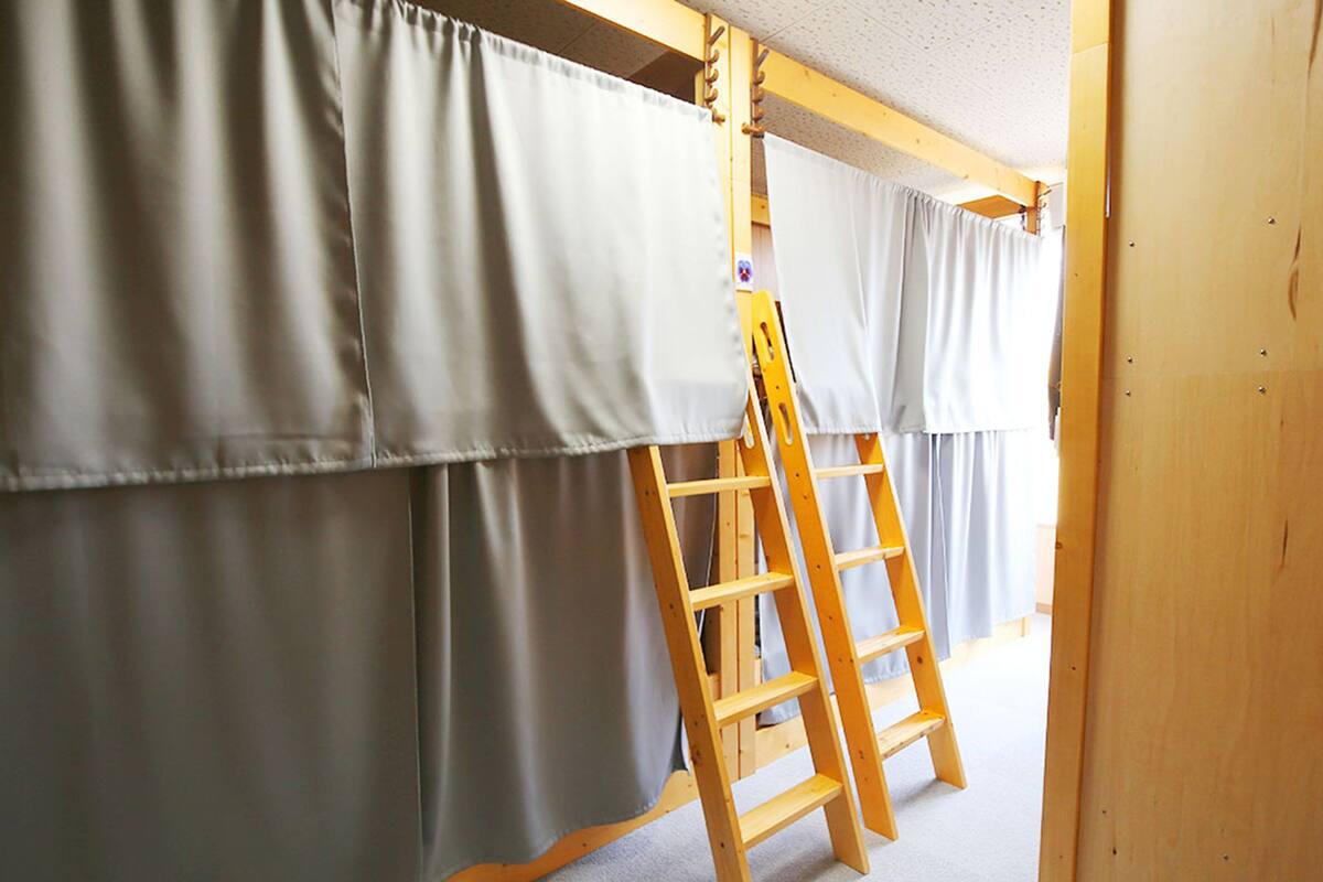 A room with a wooden ladder leaning against a wall with grey curtains.