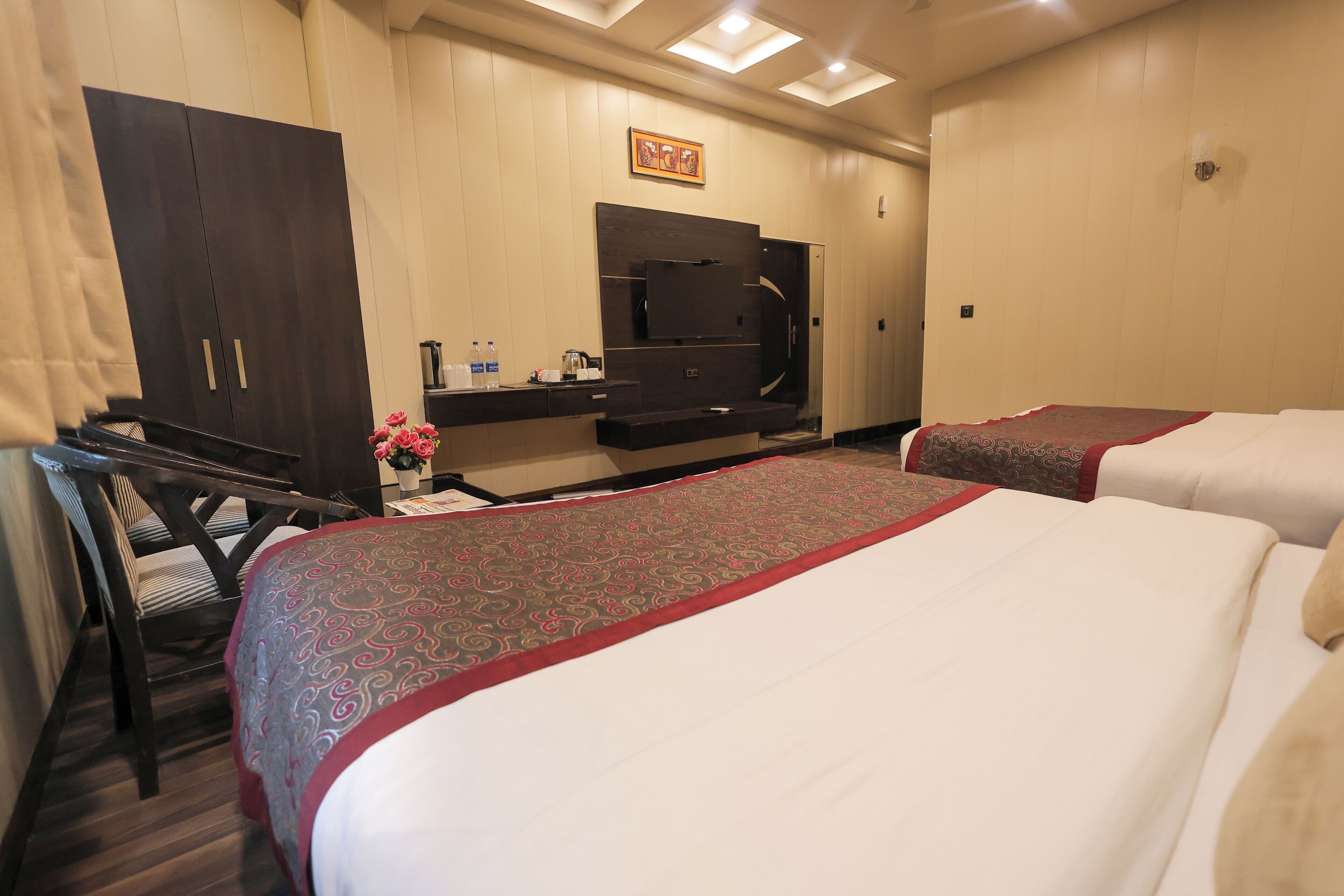 Ein Hotelzimmer mit zwei Betten, einem Schreibtisch, einem Stuhl, einem Kleiderschrank und einem Fernseher.