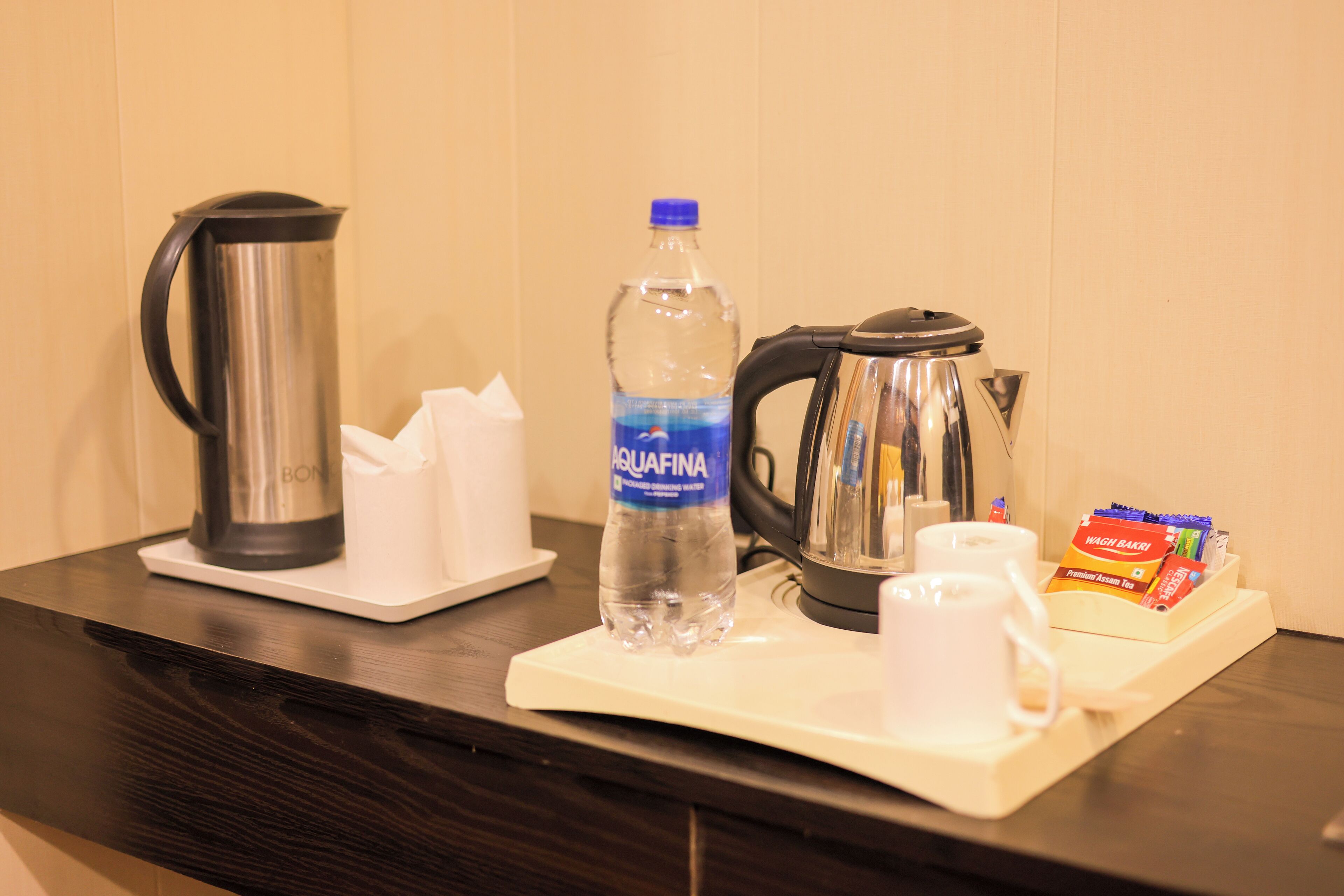 A coffee station with a water bottle, coffee pot, and tea packets.