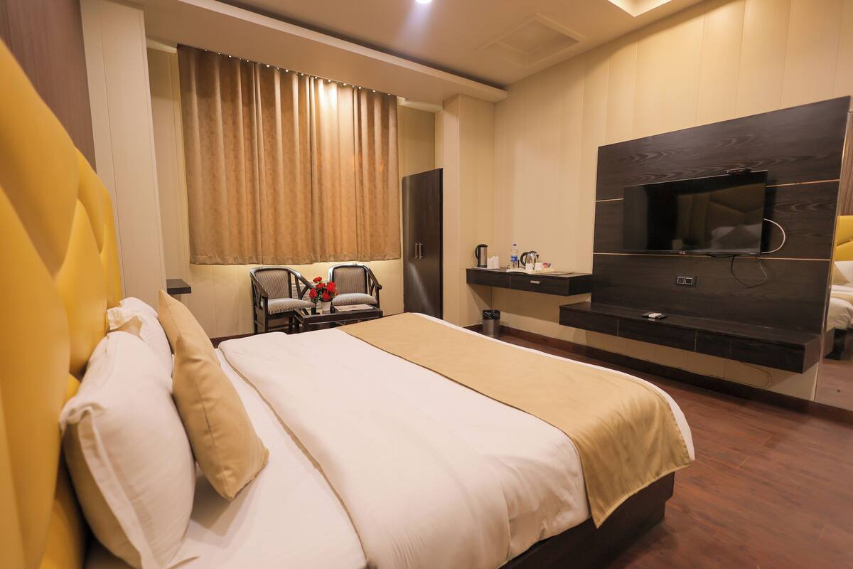 Habitación de hotel moderna con una cama grande, un televisor de pantalla plana montado en la pared, un escritorio con una silla y un minibar.