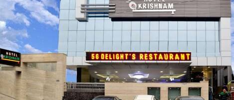 Un moderno edificio de hotel con un letrero que dice 'Hotel Krishnam' y 'Restaurante 5G Delight's' en la fachada.