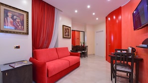 Una sala de estar moderna con un sofá rojo, un comedor con mesa y sillas, y un televisor fijado a la pared.