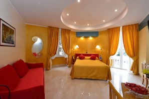 Relax in this stylish room with a large bed, sofa, and round mirror.