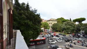 Una calle urbana concurrida, un autobús rojo, coches aparcados y motocicletas.
