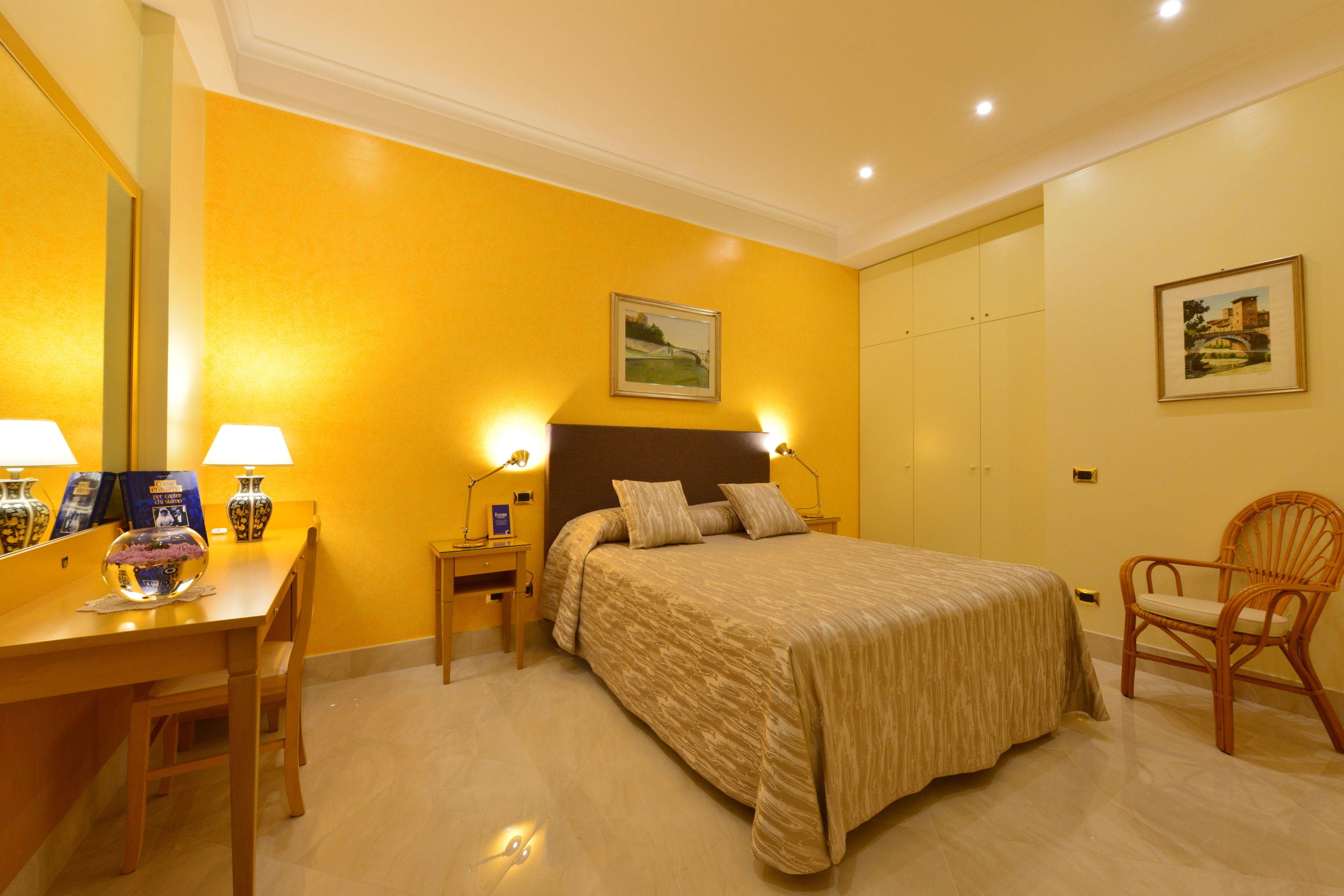 A hotel room with a bed, a desk, two lamps, and a chair.