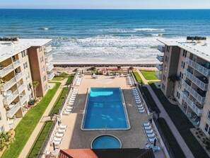 A hotel with a pool, beach view, and multiple balconies. - Ground Floor Unit Patio Ocean View Clean & Sparkling (New Smyrna Beach)