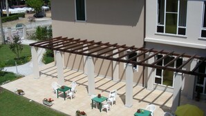Un espacio de patio cubierto con mobiliario exterior y una estructura de pérgola.