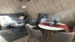 Moderni olohuone, jossa on harmaa sohva, pyöreä sohvapöytä ja ruokapöytä tuoleineen.