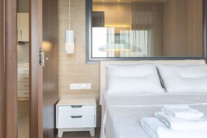 A hotel room with a bed, a nightstand, a wall-mounted lamp, and a window with blinds.