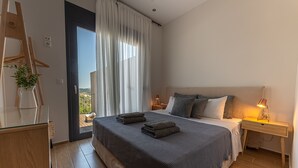 A modern bedroom with a large bed, a wooden dresser, and a desk with a lamp. - 3 Br 2 Bth Superior Villa  Cassiope with , Private Pool And Stunning Sea Views (Achladies)