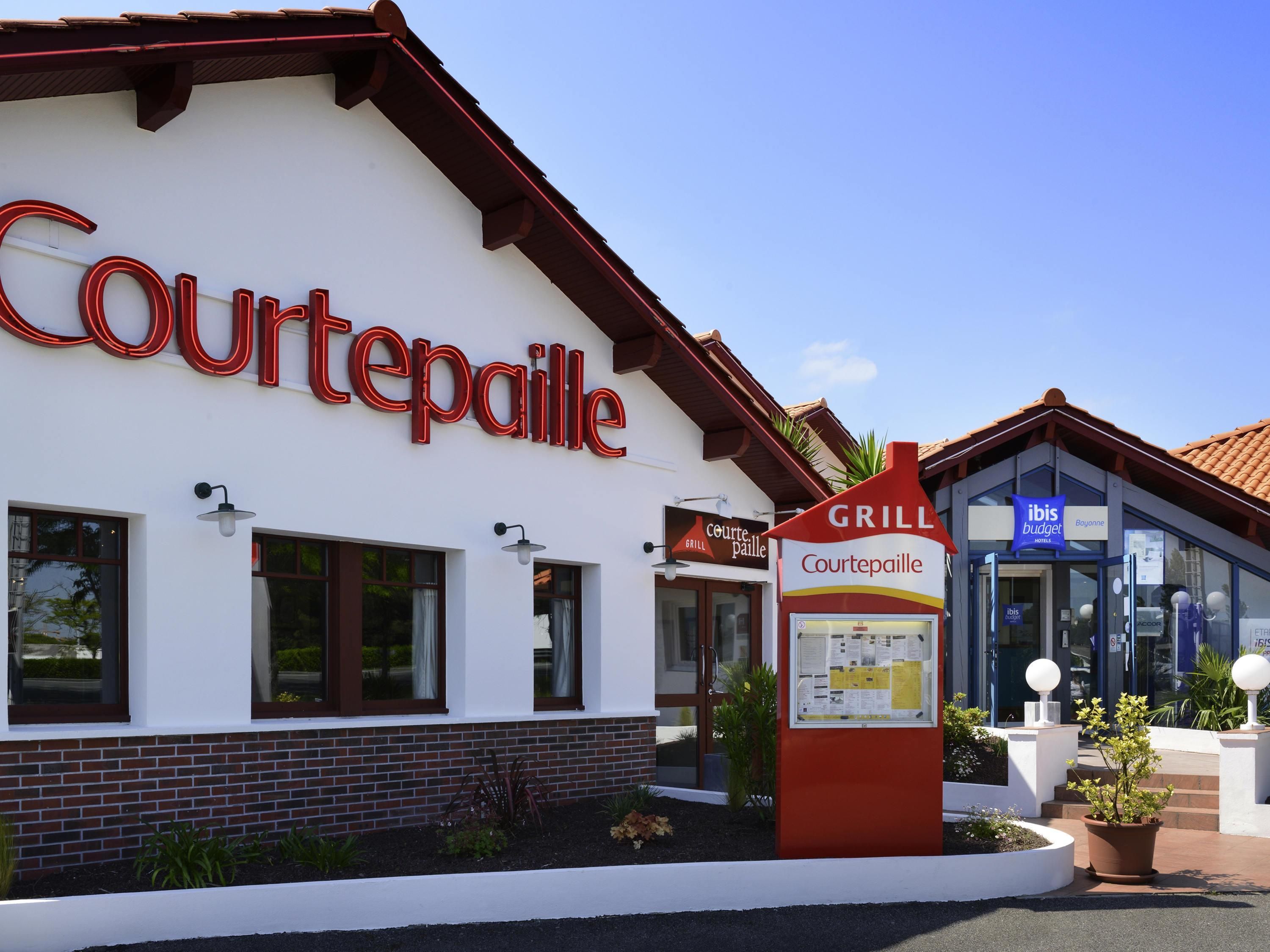 Un bâtiment Courtepaille avec une enseigne indiquant un restaurant-grill et un hôtel économique situé à proximité.