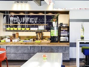 Un área de cocina moderna con un sistema tipo bufé, incluyendo una barra con alimentos y una cafetera.