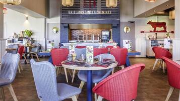 A restaurant with a central bar area, red and blue chairs, and hanging light fixtures.