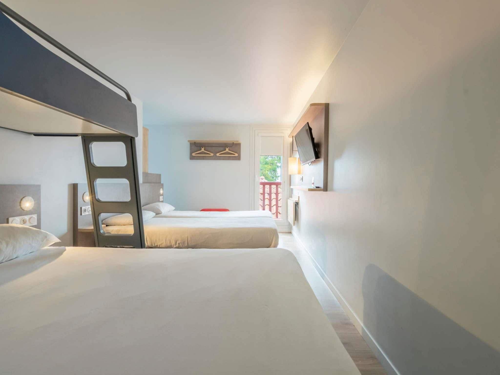 Une chambre d’hôtel moderne avec deux lits, une télévision et un balcon.