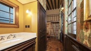 Un corridoio stretto con pavimento in legno, un lavandino bianco e una porta in legno.
