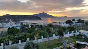 A coastal town with a mountain in the background, a body of water, and residential buildings. - Belvedere (Procida)