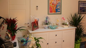 A reception desk with potted plants, a framed artwork, and various wrapped gifts. - Belvedere (Procida)