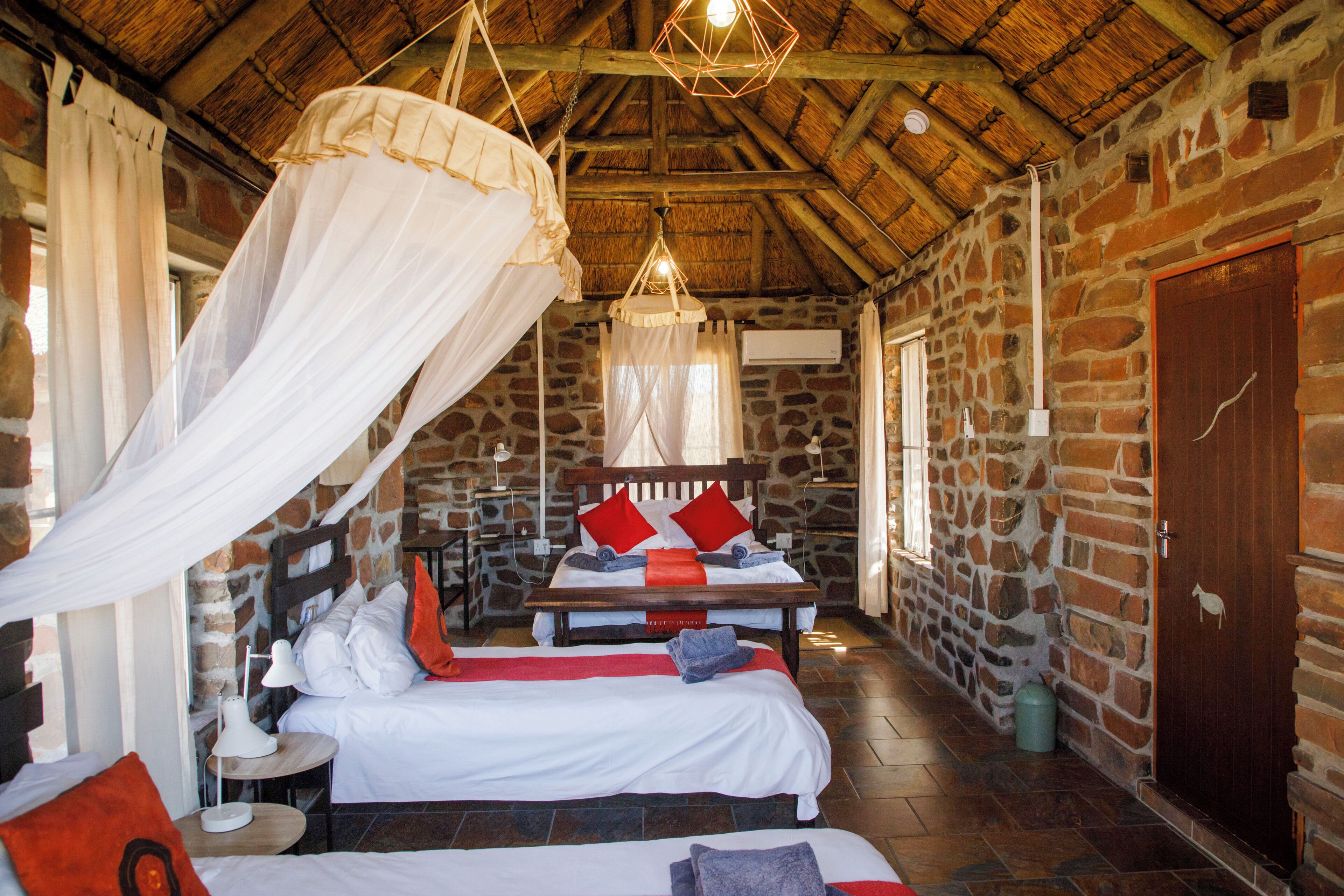 A rustic room with a stone wall, a wooden bed with a canopy, and a stone floor.