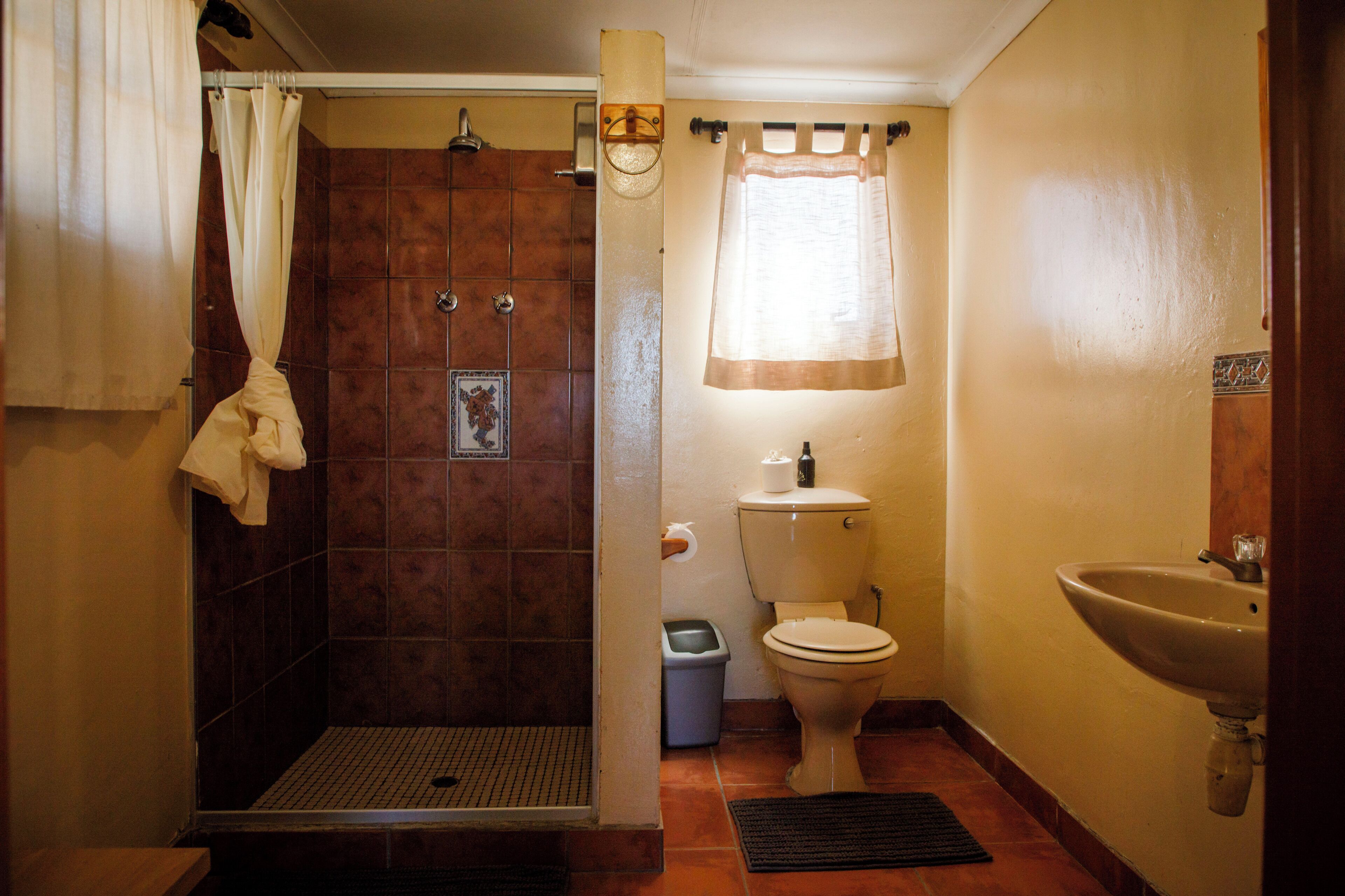 A bathroom with a shower, toilet, sink, and a towel hanging on the wall.