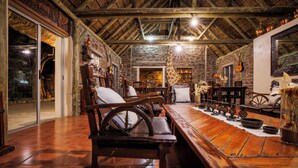 A rustic interior with stone walls, wooden furniture, and a thatched ceiling. - Tsauchab River Lodge (Sesriem)