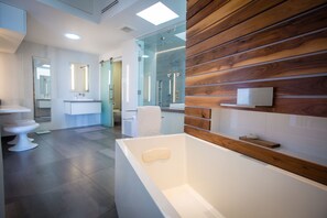 A modern bathroom with a large bathtub, a glass shower enclosure, and a wooden accent wall.
