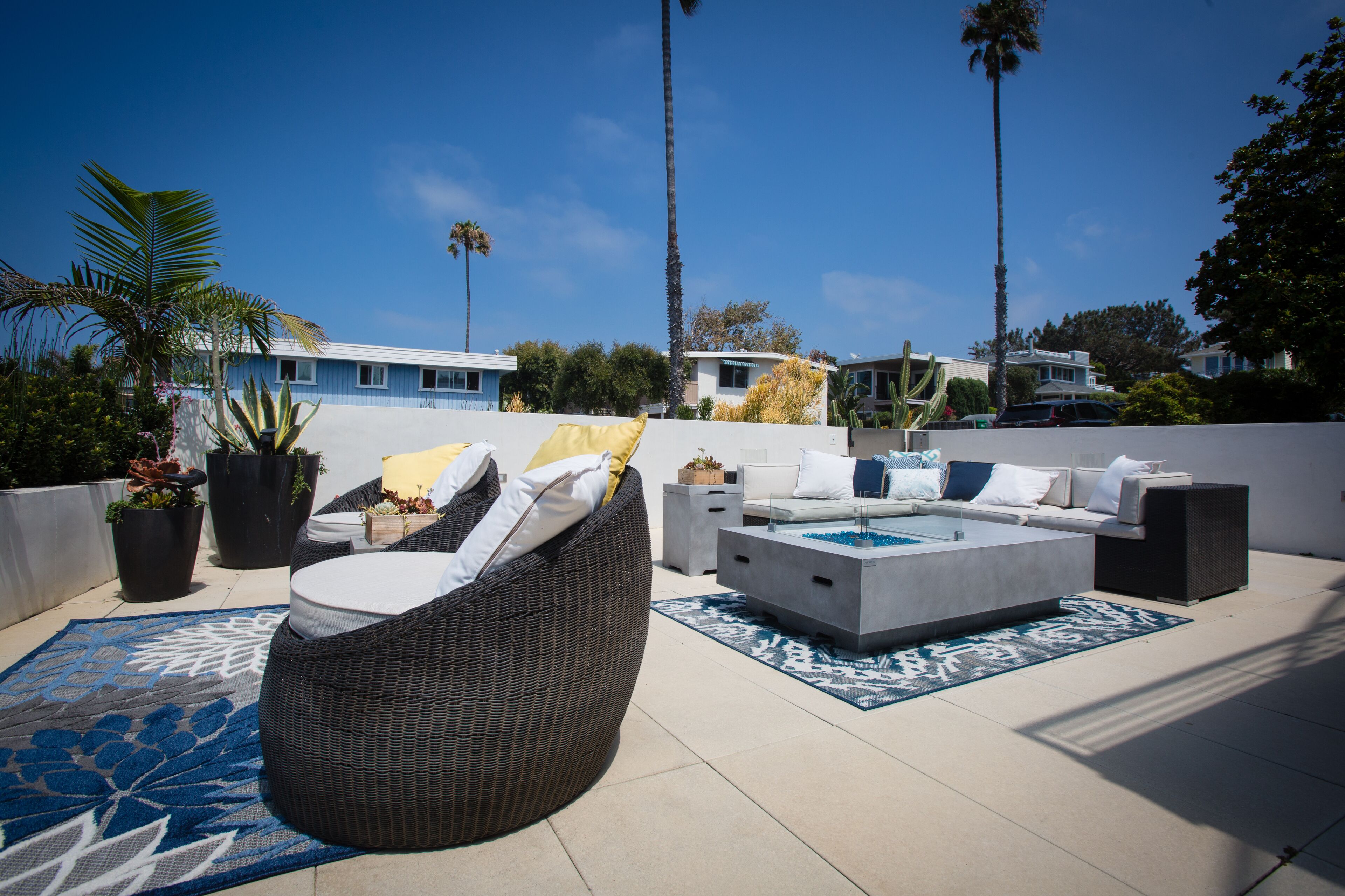 A rooftop patio with outdoor furniture, a pool, and palm trees.