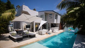 A modern house with a swimming pool, outdoor seating, and palm trees. - Modern Del Mar Beach Home (Del Mar)