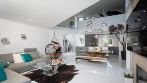 A modern living room with a glass coffee table, a sofa, and a hanging light fixture. - Modern Del Mar Beach Home (Del Mar)